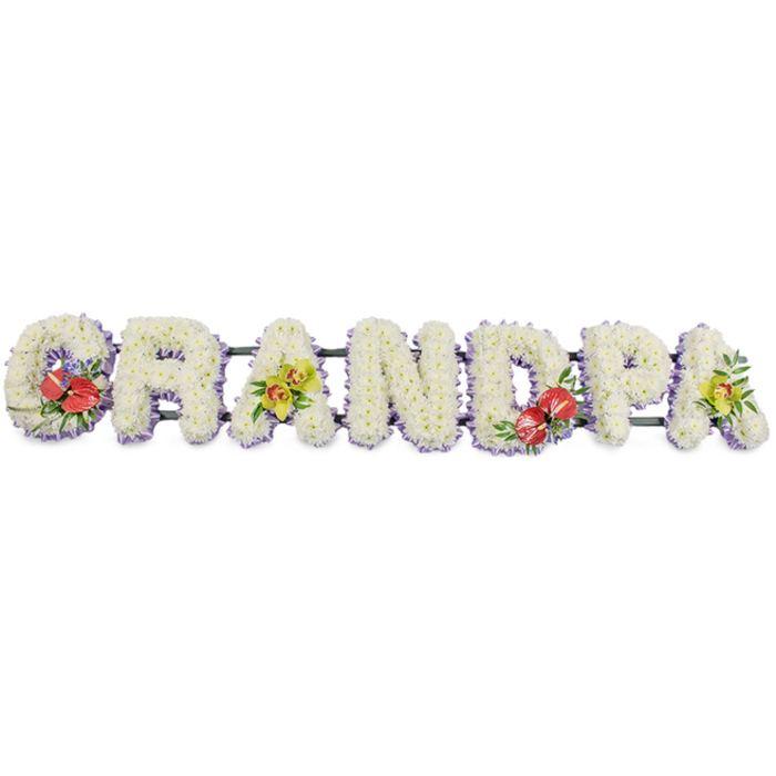 This striking funeral tribute presents the word "GRANDPA" spelled out in large, block letters, arranged in a horizontal line as if set along the edge of a coffin or at the front of a service in Bracknell Forest. Each letter is meticulously covered in dense clusters of small white chrysanthemums, their neatly layered petals creating a rich, textured surface that looks soft to the touch. The uniform white blooms convey a feeling of peace, purity, and quiet respect, making the arrangement suitable for a dignified farewell. Around the base of each letter runs a delicate trim of pale lavender ribbon, the soft purple edging just peeking through between the flowers and their framework. This subtle lilac halo adds definition and a gentle touch of colour without disturbing the overall calm appearance. The letters are held together by slender dark green bars that provide hidden strength, allowing the tribute to be moved and displayed with ease. Thoughtfully arranged sprays of accent flowers lend depth and emotional resonance. On the "G", a bold cluster of deep red anthuriums with glossy, heart-shaped spathes and yellow spadices is nestled among polished green foliage and perhaps tiny hints of purple filler blooms. The first "A" carries a grouping of yellow-green orchids, their graceful, exotic petals and slender stems arranged with lush leaves. The "D" repeats the dramatic red anthuriums, visually echoing the "G" and adding balance, while the final "A" mirrors the first "A" with another cluster of delicate yellow-green orchids. The design feels personal and bespoke, the kind of arrangement families in Bracknell Forest choose to say a last, loving goodbye to a grandfather, expressing enduring love, respect, and treasured memories.