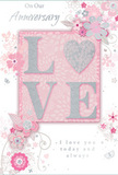 Captured in soft, even lighting, this anniversary card offers a delicate celebration of long-lasting love, as if ready to be paired with a bouquet arriving at a doorstep in Bracknell Forest. The main feature is the word LOVE, placed prominently at the centre and formed from gently raised glitter that glows rather than sparkles harshly. The O is transformed into a shimmering, silver-textured heart, providing a simple yet striking focal point that symbolises the core of the relationship it honours. Surrounding this central motif, a ring of pastel blooms unfolds in shades of blush, mauve, and soft ivory. The flowers have an almost watercolour softness, with fine, flowing outlines and gentle shading that hint at depth without appearing heavy. Delicate curls of vines, loose petals, small swirls, and subtle butterfly silhouettes drift across the design, invoking the feel of an English spring garden after a light shower, not unlike the green spaces scattered through the Bracknell Forest area. The background remains a calm blend of soft pinks and silvery greys, giving the entire card an atmosphere of treasured intimacy. Text reading On Our Anniversary and I love you today and always appears in a graceful, understated script that echoes the flowing movement of the illustrated vines. The overall composition feels quiet yet deeply heartfelt, like a whispered promise shared over many years, making this card a fitting keepsake to sit alongside fresh anniversary flowers delivered to homes throughout Bracknell Forest.